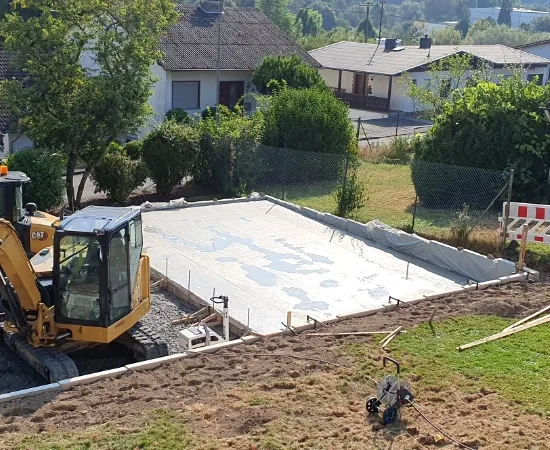 Bagger und frisch gegossenes Fundament für eine Fertiggarage