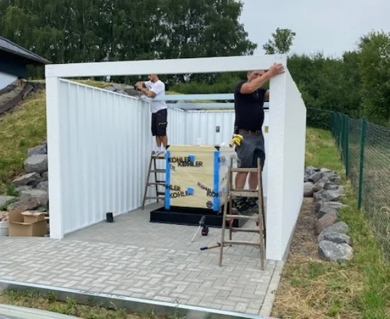 Zwei Monteure bauen die Wände einer Stahlgarage auf