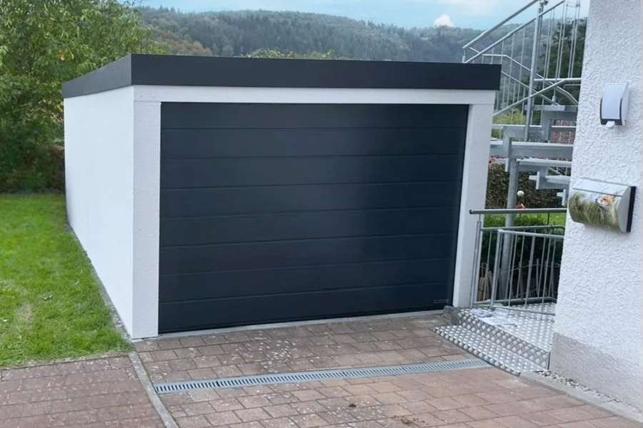 Einzelgarage mit anthrazitfarbenem Sektionaltor am Wohnhaus